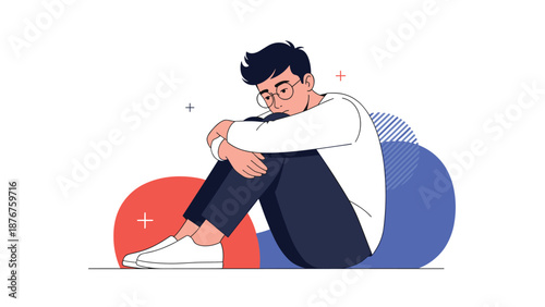 Sad young man sitting on the floor and hugging his knees in distress to represent mental health issues and social anxiety.