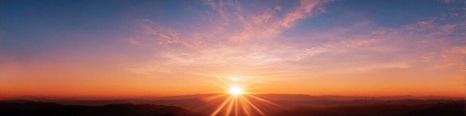 Vibrant sunrise over mountainous horizon with radiant clouds