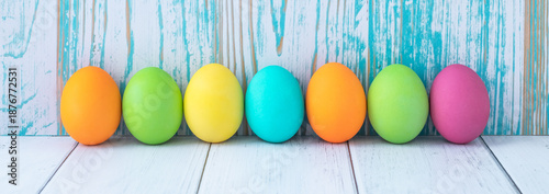 Colorful Easter eggs on blue and white wooden background. Easter card, festive background, paschal mockup, empty space. Holiday banner.