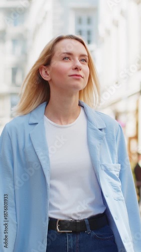 Portrait of young blonde tourist woman walking on urban city street outdoors. Smiling happy lady girl traveler having positive good mood enjoying in summer daytime. Town lifestyles, vacation holidays