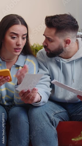 Stressed young family marriage couple man woman looking at unpaid bank debt bills, doing paperwork, planning budget, calculate finances mortgage payments. Husband wife together throws home paper bills