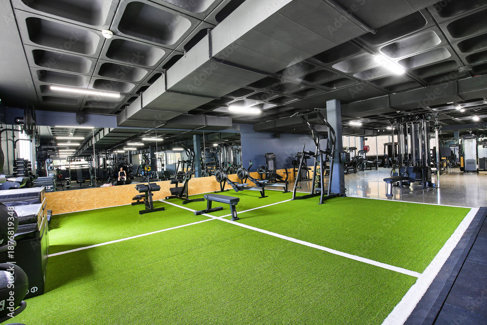 Obraz premium A modern gym filled with energy, featuring strength machines, free weights, and cardio equipment. Bright lights, mirrors, and focused people create a motivating space for fitness and strength. 