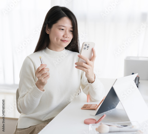 A woman is taking a selfie with lip balm and her phone.