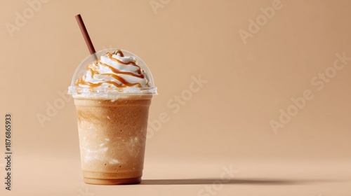 Iced caramel frappuccino with whipped cream in plastic cup on beige background