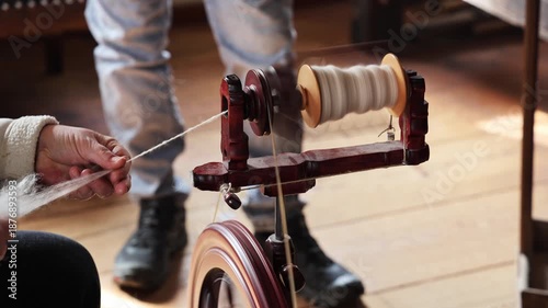 Woman spinning on an old wooden spinning wheel