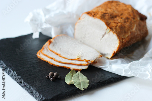 Quadro su tela Sliced roasted pork loin served on parchment paper on a slate serving board
