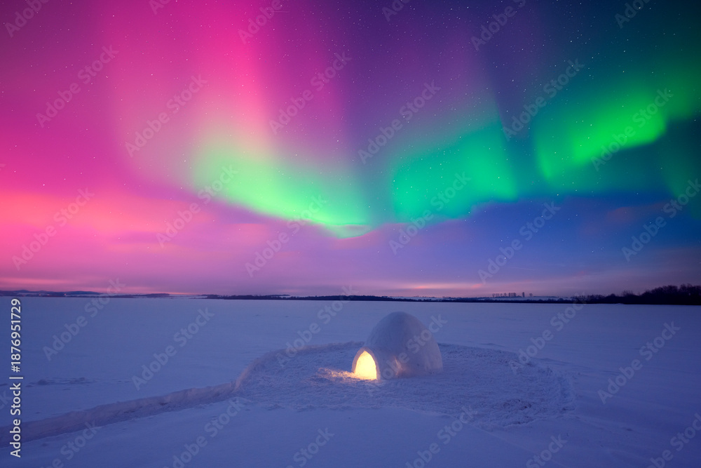 Obraz premium A lonely igloo glowing from inside in a frozen snow field with Aurora borealis in night sky. Northern lights in winter field. Wintry scene with glowing polar lights and snowy igloo. Christmas postcard