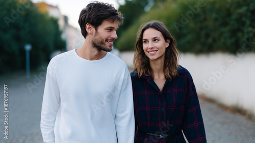 a young affectionate couple walking hand in hand along a quiet city street, looking at each other with love and connection. 