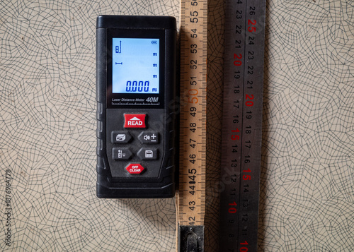 Tableau sur toile Digital laser distance meter on a wooden ruler background