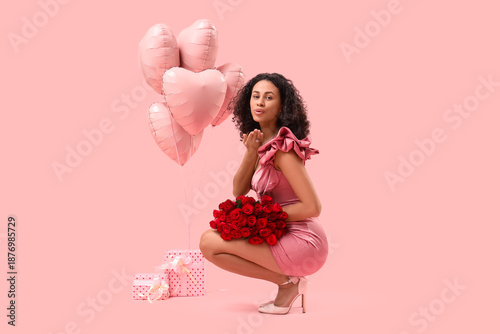 Beautiful young African-American woman with bouquet of roses and heart-shaped...