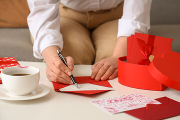 Woman writing love letter at table. Valentine's Day celebration