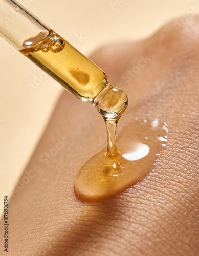 golden oil is pouring out of a glass dropper on dark skin, macro texture of the skin on which the oil is applied
