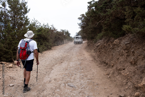Schilderij op canvas Man hiking on dirt road toward adventure vehicle. Nature Safari