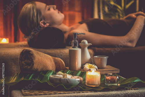 Canvas Print Aromatherapy massage ambiance or spa salon composition setup with focus decor candles and spa accessories on blurred woman enjoying blissful aroma spa massage in resort or hotel background