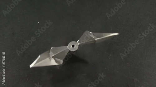 Wallpaper Mural Geometric Metal Object on a Dark Surface: A sleek, modern metal object with sharp angles and a central hole rests gracefully against a dark backdrop, perfect for an industrial or artistic design. Torontodigital.ca