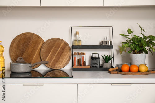 Electric stove with cooking pot and utensils on white counter in modern kitchen © Pixel-Shot