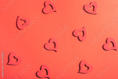 Scattered wooden heart shapes on red background. Valentines day concept, pattern