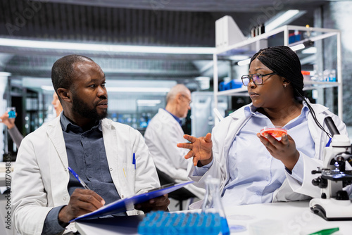 Valokuva Team of lab specialists working together to check bacterial growth on petri dish