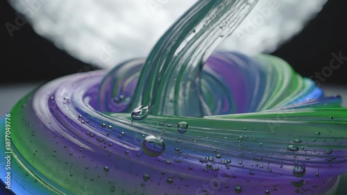 Satisfying macro video of a colorful, transparent, and viscous slime stretching and dripping with small air bubbles, creating an oddly satisfying asmr visual against a dark background