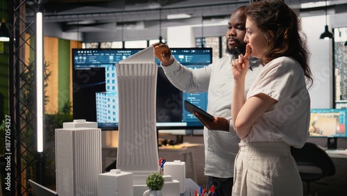 Photos Property developers discuss the challenges of city planning and land acquisition, using 3D models to visualize residential layout expansion and infrastructure upgrades on the table