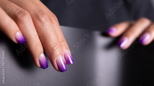Professional purple ombre manicure on woman hands. Stylish nail art, cosmetics and self care concept on dark background.