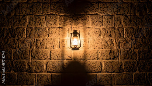 lit lantern on stone wall at night
