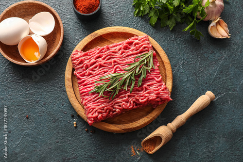 Tableau sur toile Plate with fresh ground meat, rosemary, eggs, parsley and garlic on green grunge