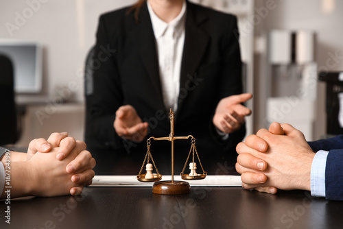 Justice scales with pawns and clients at table in mediator's office, closeup