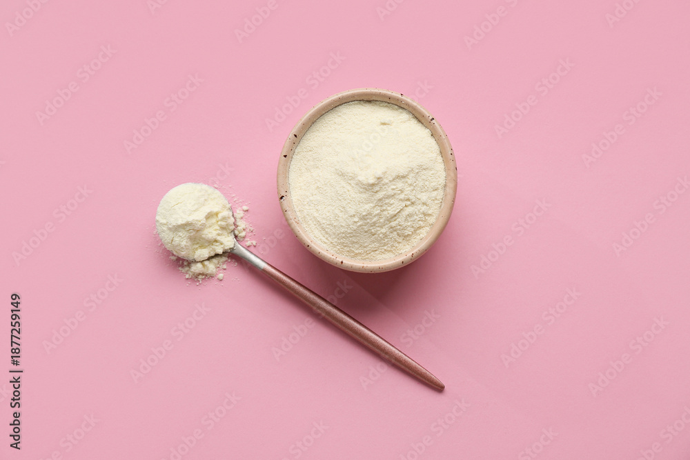 Naklejka premium Bowl of powdered milk with spoon on pink background