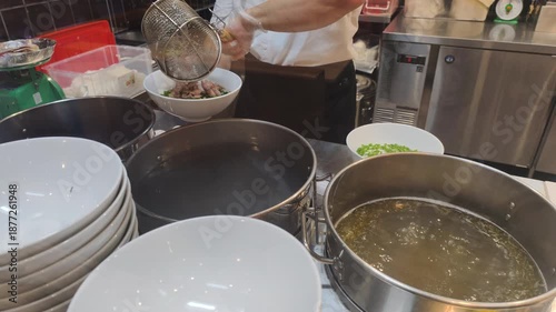 Authentic Pho Cooking requires time. Chef demonstrates Authentic Pho Cooking in restaurant. This Authentic Pho Cooking includes boiling beef in large pot to make traditional tasty broth.