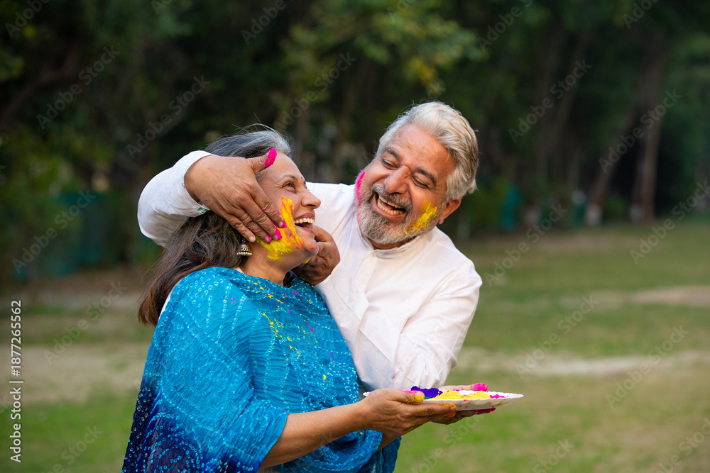 Naklejka premium Indian senior couple playing colors and celebrating holi festival