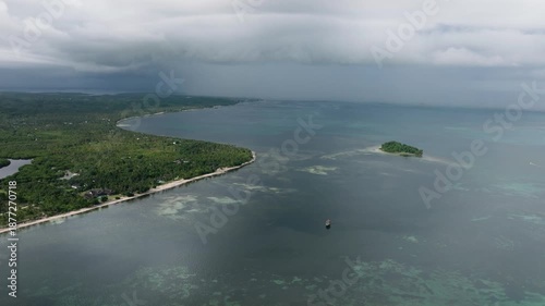 Aerial view of coastline with forested land and a nearby small green island. Siargao, Philippines.