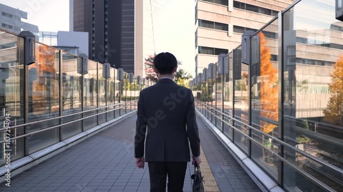 歩道を歩くビジネスマンの後ろ姿のフォローショット