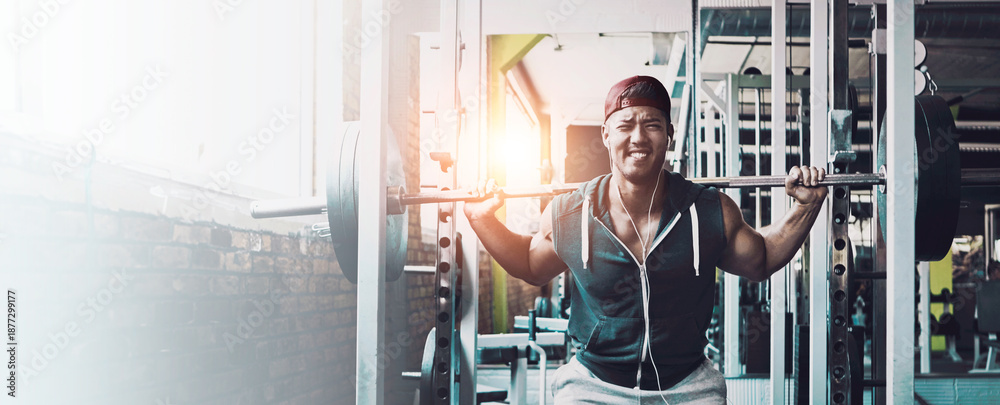 Fototapeta premium Weights, music and barbell with man in gym for fitness equipment, streaming playlist and health. Exercise, earphones and bodybuilder with person in center for weightlifting for muscle and space