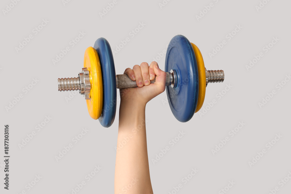 Obraz premium Female hand with dumbbell against grey background, closeup