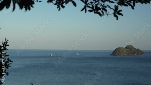 島と岩礁の灯台の間を抜けて沖へ向かう船