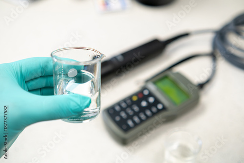 Photos Woman hand in gloves adjusting a pH meter for water analysis