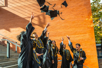 Diverse students celebrating graduation tossing caps in air