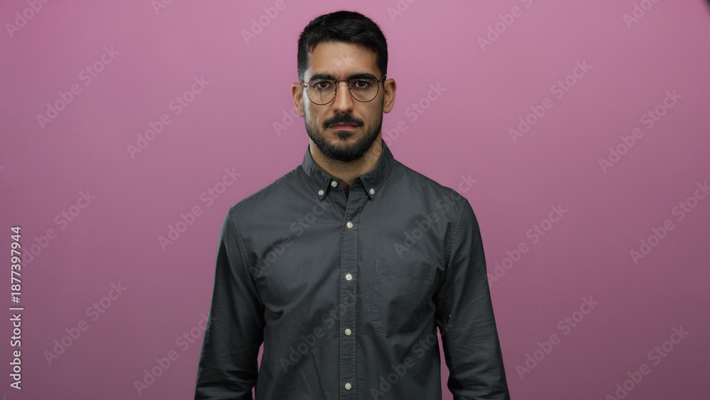 Obraz premium Man standing confidently against a vibrant pink background wearing glasses and a buttoned shirt, exuding a calm and poised demeanor with a modern style.