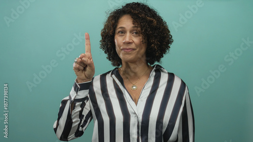 Photos Woman in a striped shirt holds up index finger adorned with a silver ring in a teal studio set; clarity insight confidence focus
