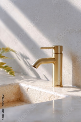 an elegant brass faucet on top of a textured stone sink, with sunlight shining through the window. a hairbrush sits beside the basin
