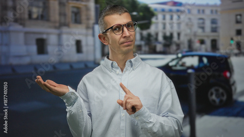 Foto Man with glasses finger wagging on street expressing disapproval in urban outdoor setting wearing striped shirt with buildings in background