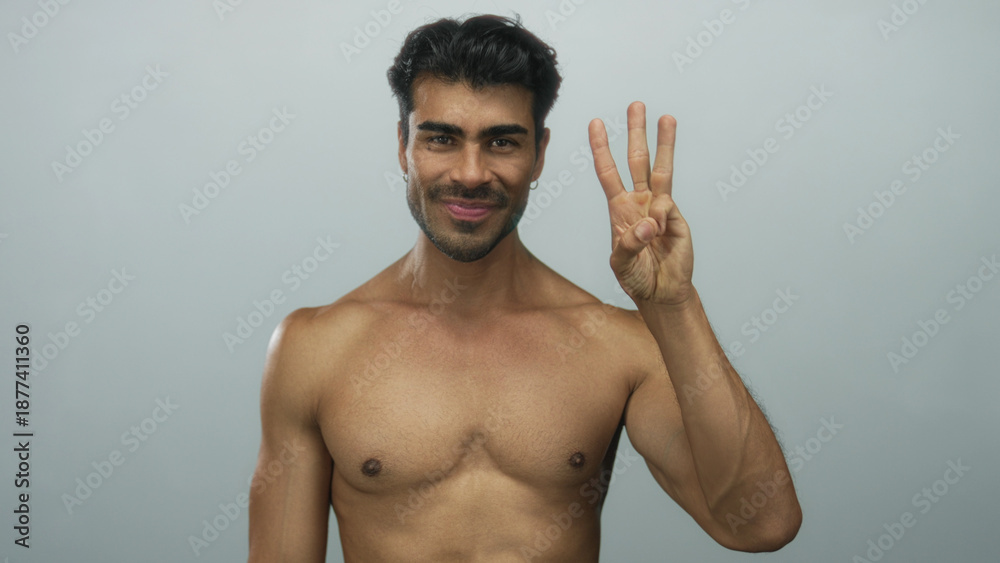 Fototapeta premium Hispanic man with muscular bare chest counting with fingers in lightblue studio on camera; confidence.