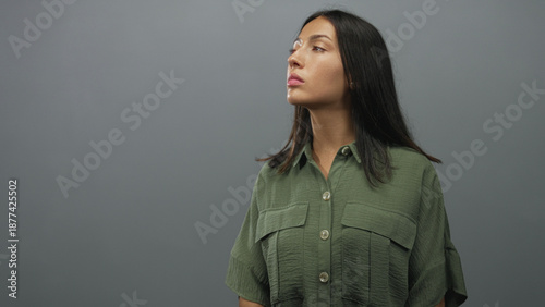 Foto Hispanic woman face and neck visible looking up in studio with green shirt and neutral gray wall; quiet contemplation