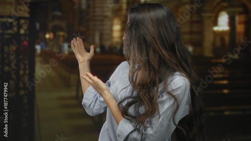 Photos Young hispanic woman gestures with both hands while smiling inside a historic church building under soft daylight; serenity