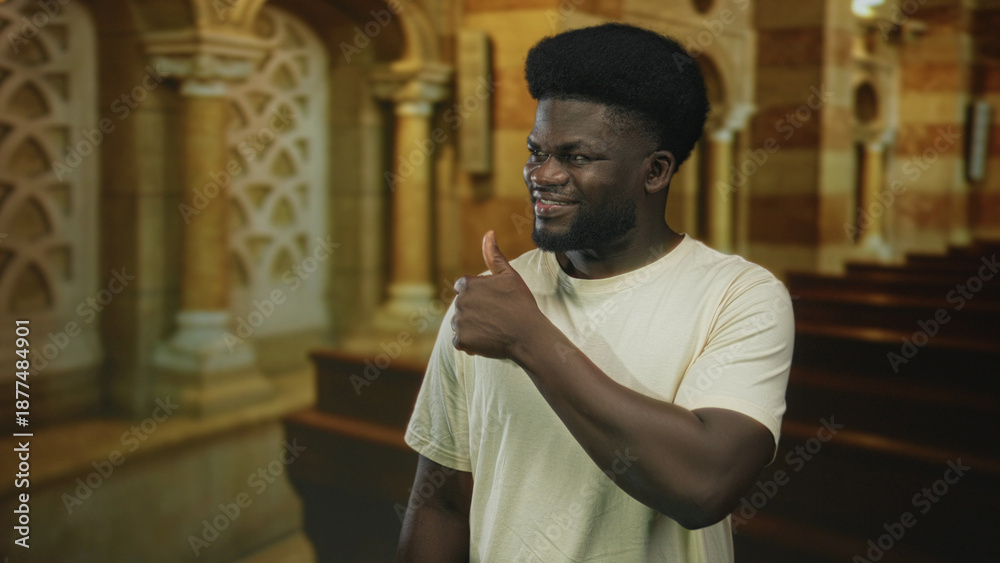 Obraz premium Man giving thumbs up with visible hand inside catholic church nave smiling toward camera; faith approval joy.