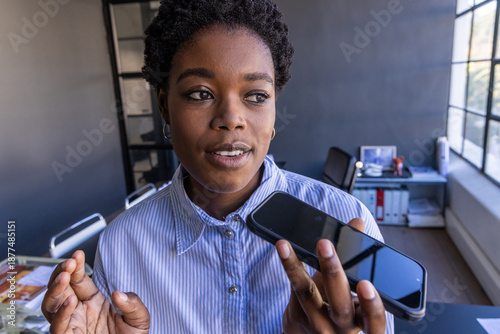 Schilderij op canvas African american woman, speaking on smartphone at office desk with laptop