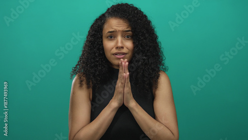 Konstfotografi Woman with curly hair and a pleading expression stands alone against a vibrant green background, creating a dramatic scene of emotion and hope