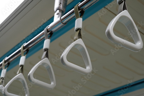 Cuadro en lienzo Row of white triangular hand grips hanging inside a subway train.