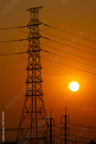 Silhouette of a high voltage transmission tower orange sunset sky. concept Industrial energy infrastructure and power lines